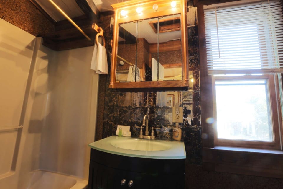 This en-suite bathroom off the guest bedroom has a combined tub & shower and ample storage space.