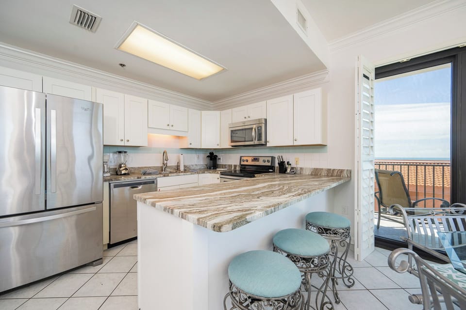 The kitchen's cool marble breakfast bar invites you to gather and share fresh coastal flavors and laughter