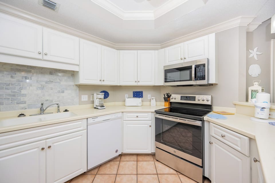 Prepare meals in this kitchen with sleek cabinetry, stainless appliances, and stylish backsplash