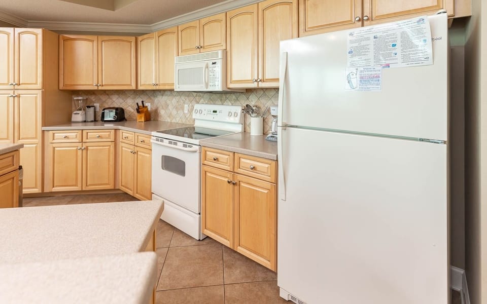 Kitchen featuring light wood cabinetry, white appliances, and ample counter space for meal preparation