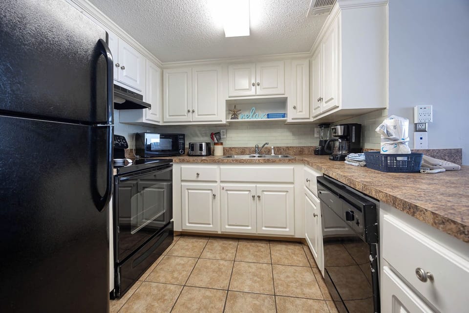 This kitchen features sleek black appliances, white cabinetry, and a welcoming atmosphere for preparing meals