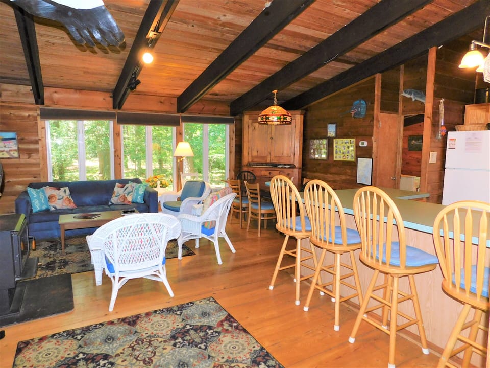 16 Middlesex Drive - Airy Great Room - The open-concept main living area features exposed wooden beams and large glass doors that open directly onto the screened porch. This bright and social space is designed for relaxed coastal living and easy entertaining.