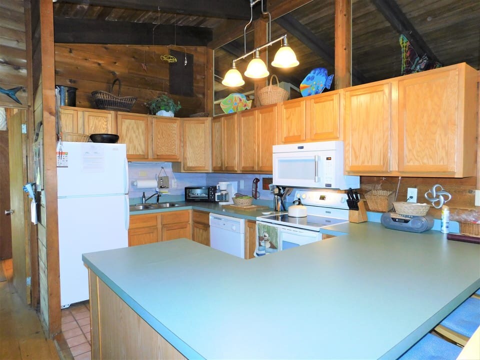 19 Addy Road - Fully Equipped Kitchen - Featuring a wrap-around counter design, this kitchen provides plenty of room for meal prep and beach snack assembly. The layout keeps the chef connected to the dining and living areas, ensuring you never miss a moment of family fun.