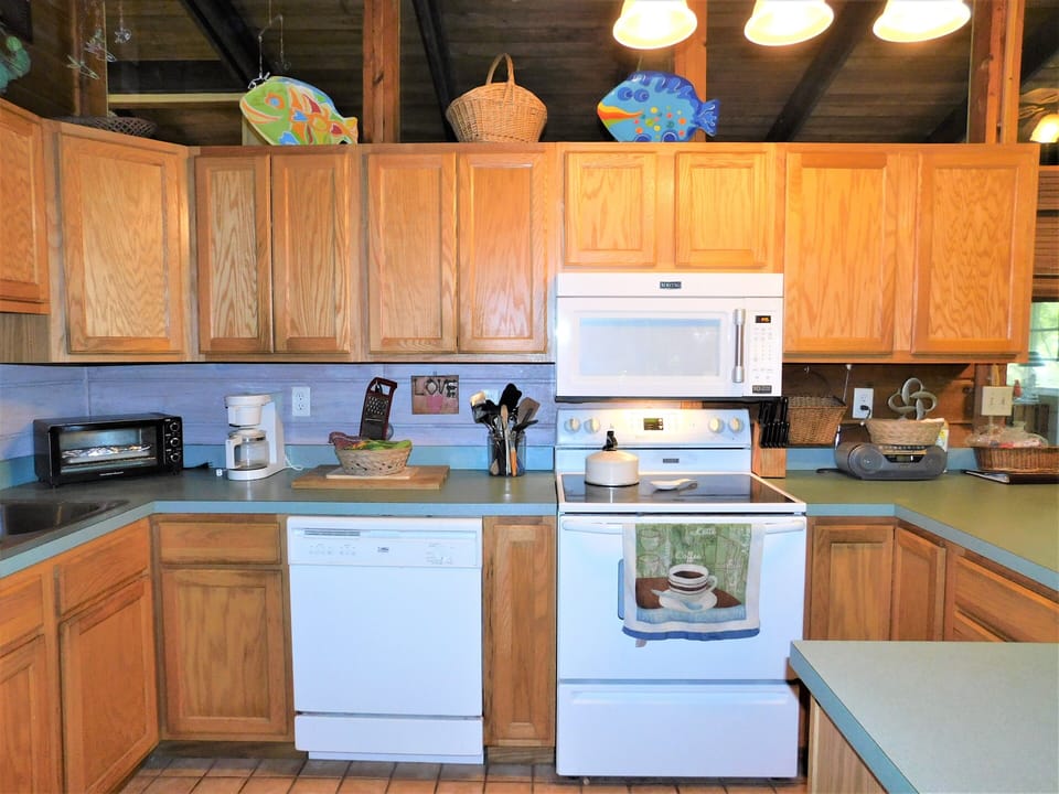 19 Addy Road - Functional Cottage Kitchen - This efficient kitchen is equipped with modern conveniences, including a white electric range, built-in microwave, and dishwasher. The warm wood cabinetry provides plenty of storage for all your vacation cooking needs.
