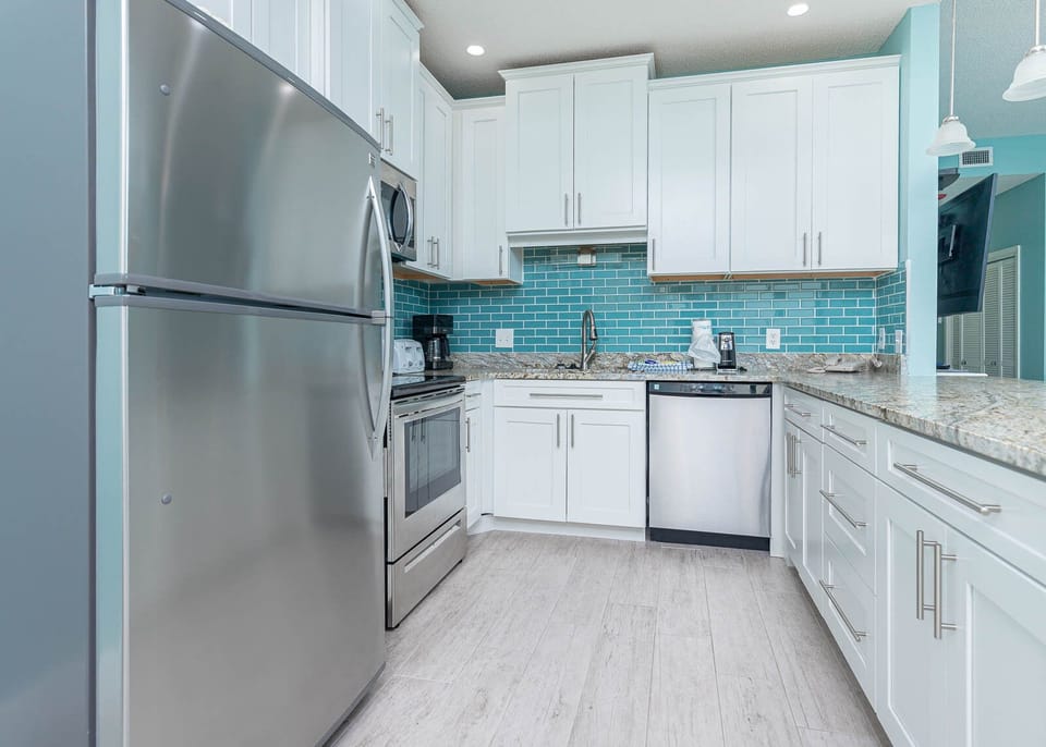 Prepare meals in this stylish kitchen featuring stainless appliances and vibrant tile accents for a delightful experience