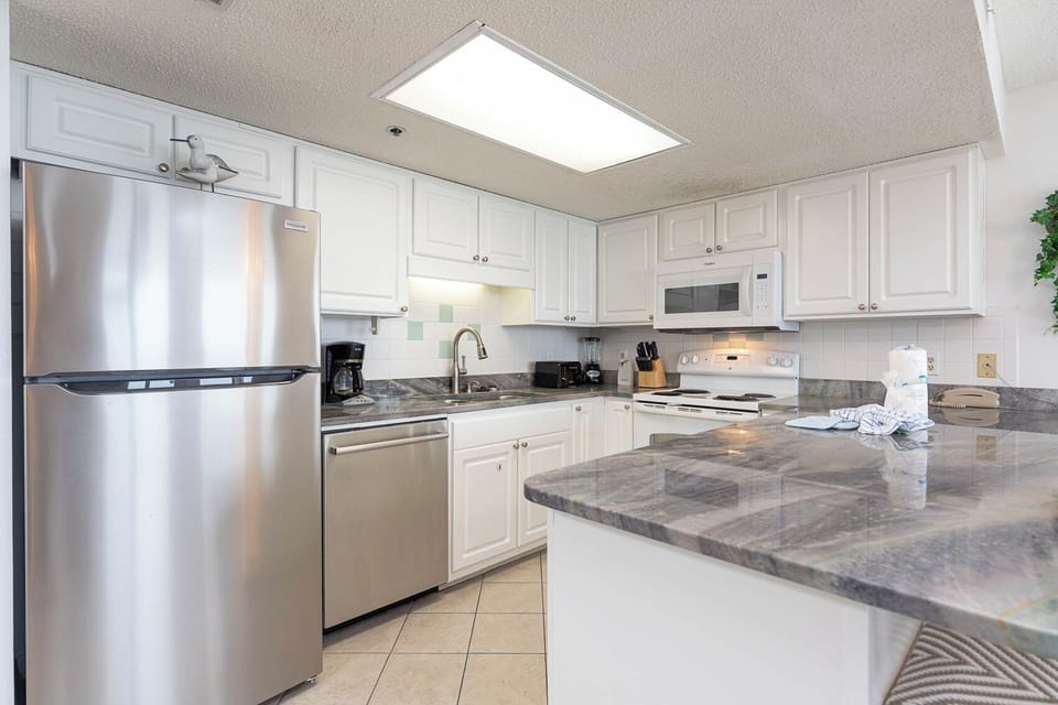 Bright kitchen features white cabinetry, granite countertops, and a convenient breakfast bar for casual dining