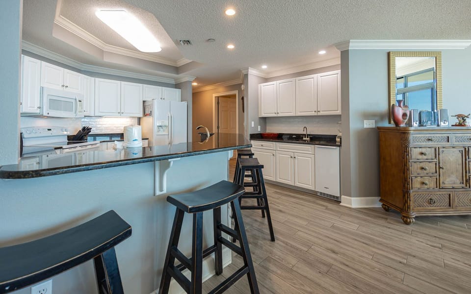Savor your morning coffee at the sleek breakfast bar, surrounded by inviting coastal decor and natural light