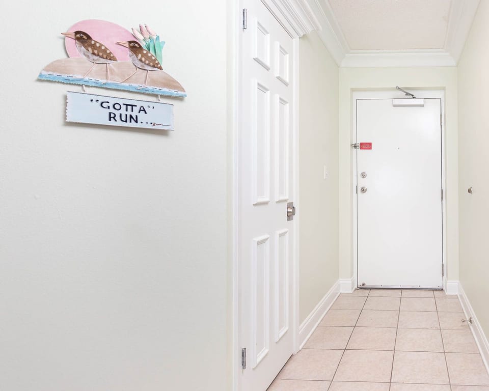 Welcoming entryway features a whimsical bird sign and tiled flooring, setting a cheerful tone for the vacation experience