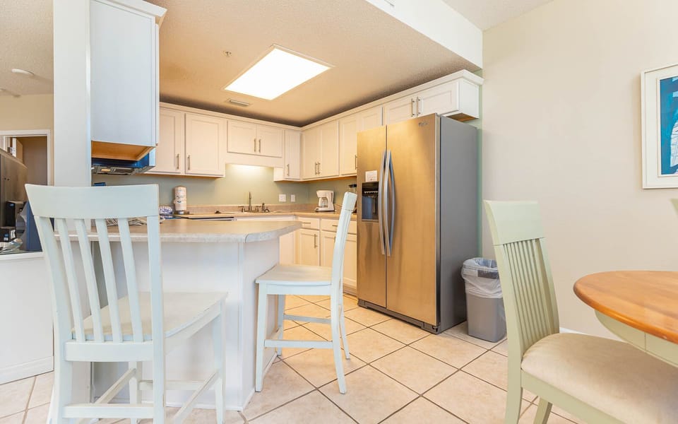 Prepare meals in the functional kitchen featuring stainless appliances and a breakfast bar with seating for two