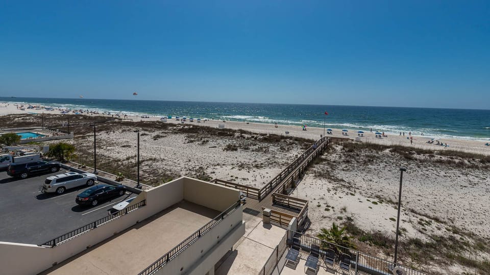 This stunning view showcases a beachfront scene with soft sand, inviting beach chairs, and a glimpse of the sparkling water
