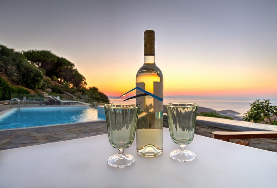 Enjoy a sip of wine by the pool  at sunset