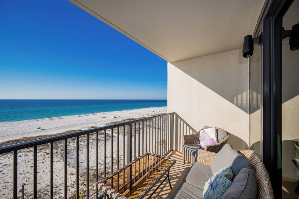 This balcony features comfortable seating and a stunning beachfront view, perfect for relaxing and enjoying the scenery