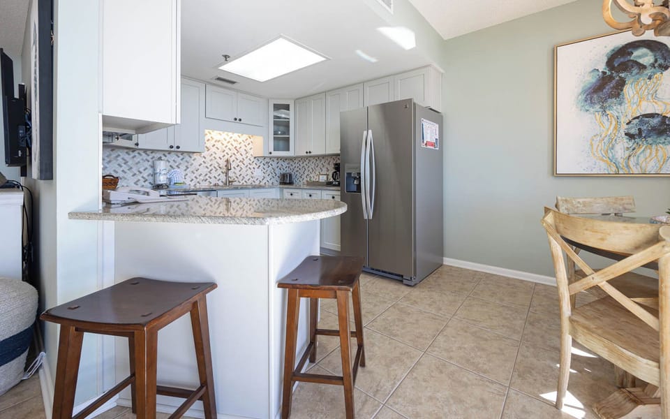 Inviting kitchen area featuring a breakfast bar with seating, sleek stainless appliances, and decorative tile backsplash