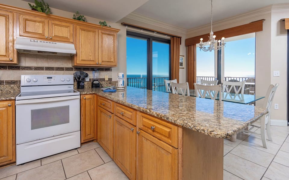 Enjoy cooking in this spacious kitchen with granite countertops and a view of the dining area and beach beyond