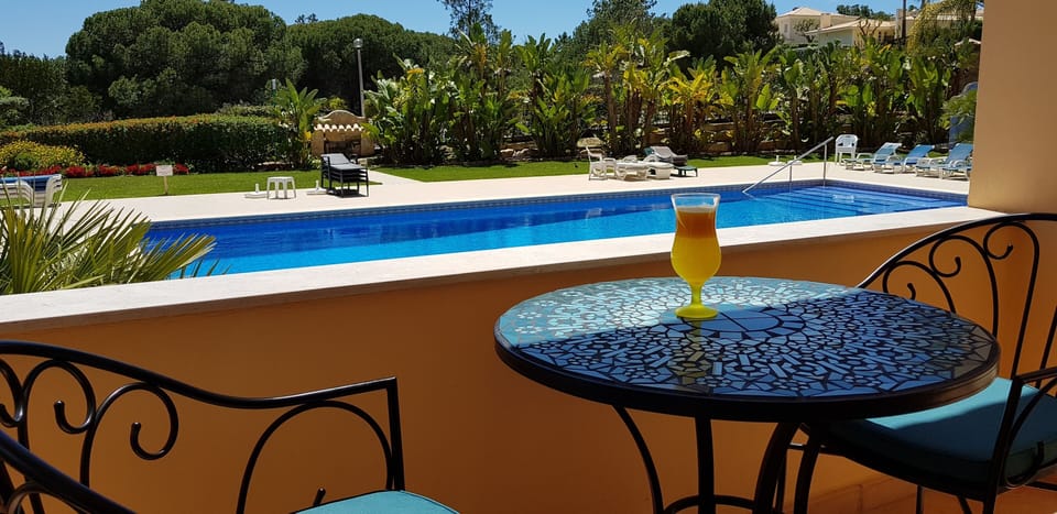 Bistro table & chairs overlooking the pool & gardens leading from master bedroom