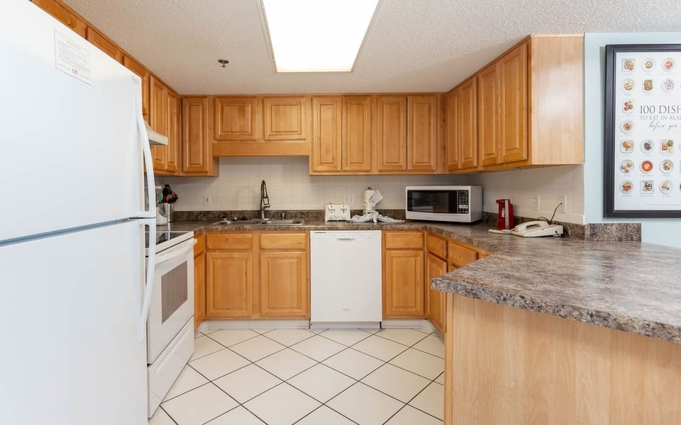 Fully-equipped kitchen featuring wooden cabinetry, white appliances, and ample counter space for meal prep