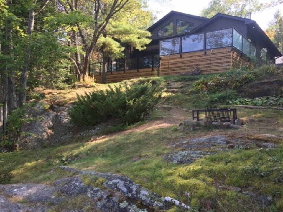 Full view of cottage with fire pit with lake views.