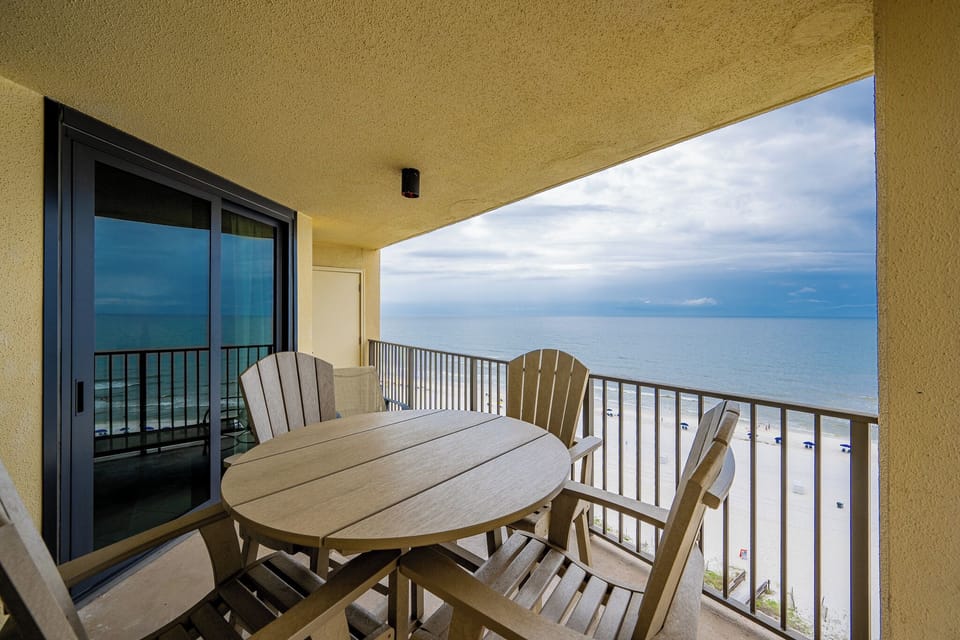 A round table with wooden chairs overlooks the beachfront, offering a tranquil spot to enjoy the scenic coastal view