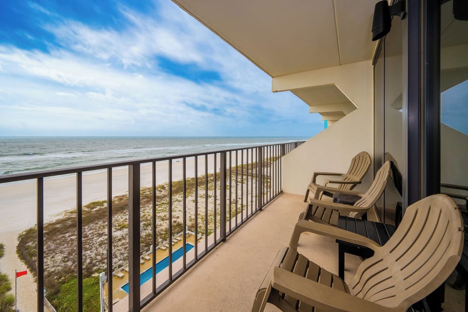 Enjoy stunning beachfront views from this private balcony, complete with comfortable seating for ultimate relaxation