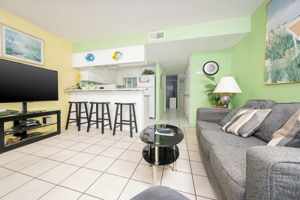 This inviting living area features a cozy couch, a sleek coffee table, and a view of the bright kitchen with cheerful decor