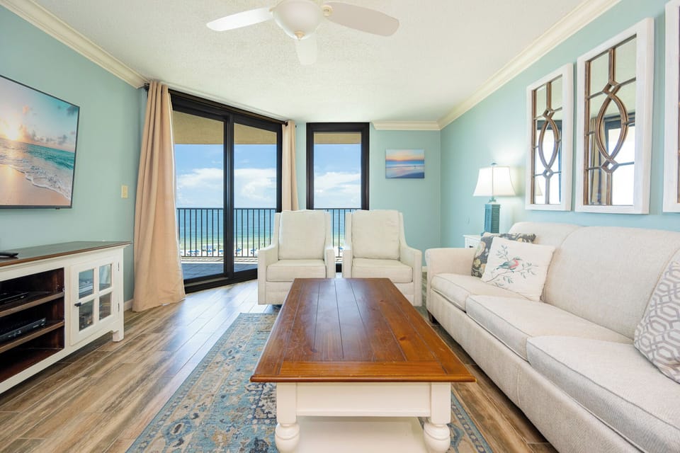 Unwind in the inviting living area, featuring plush seating, a large TV, and stunning beach views