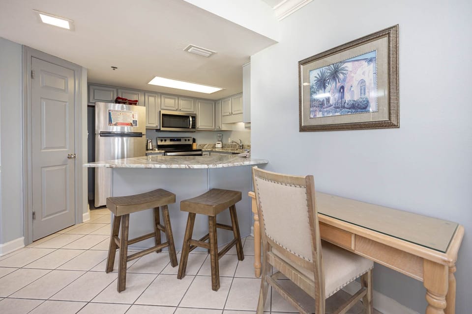 Kitchen area featuring a breakfast bar with wooden stools, sleek appliances, and a cozy workspace with complementary WiFi