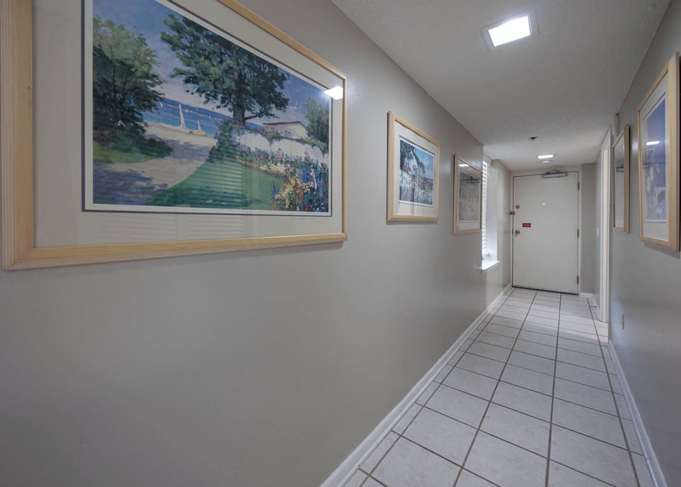 Walk through a charming hallway adorned with coastal artwork, leading to your inviting vacation space