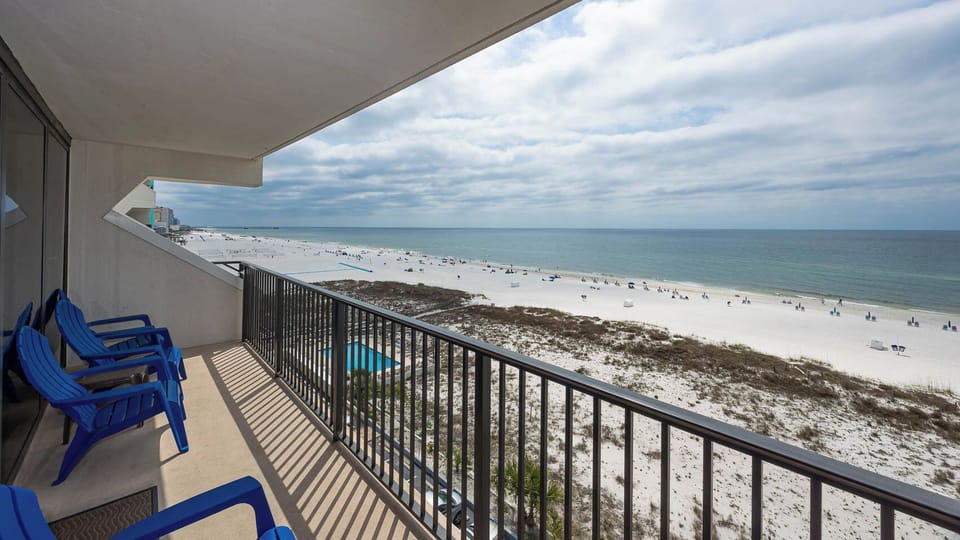 Enjoy a stunning beachfront view from the balcony with bright blue chairs, perfect for relaxation and soaking in the scenery