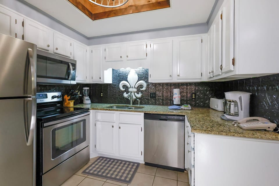 This kitchen features sleek stainless appliances, granite countertops, and a cozy coffee maker for your convenience