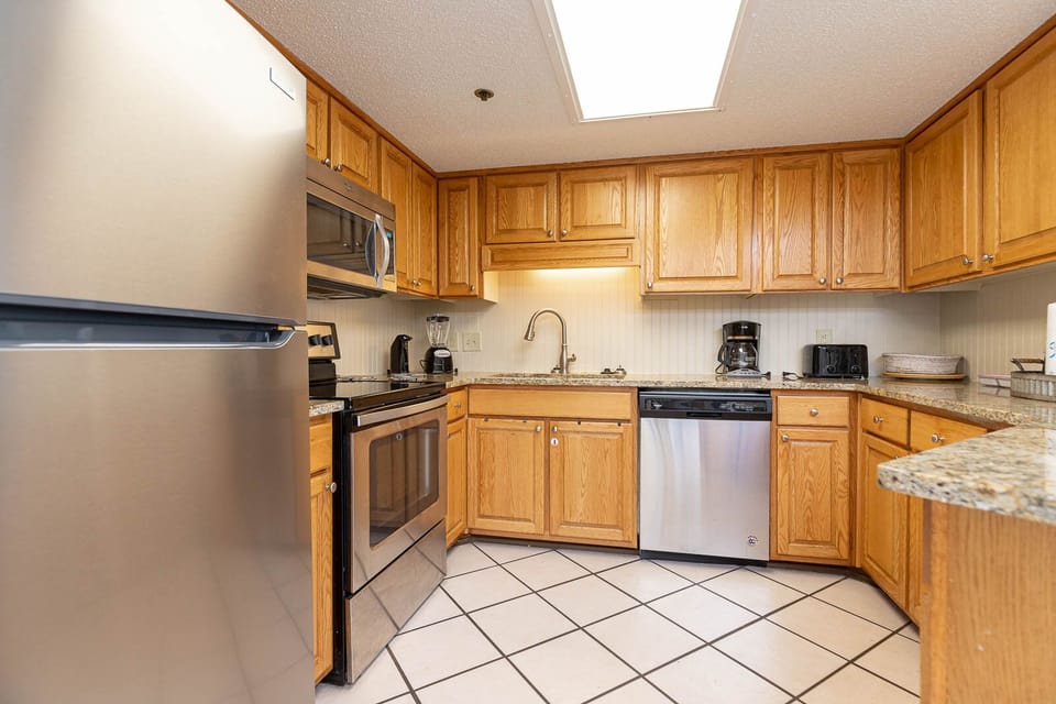 Kitchen featuring wooden cabinetry, granite countertops, and a bar area, perfect for preparing meals and entertaining