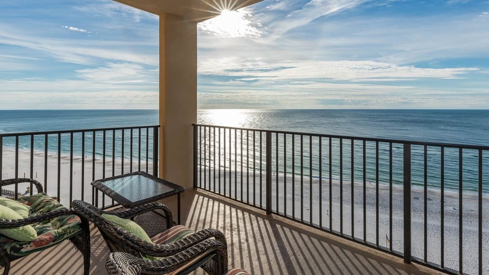Relax on the balcony with comfortable seating, enjoying the sparkling water and serene beach view just below