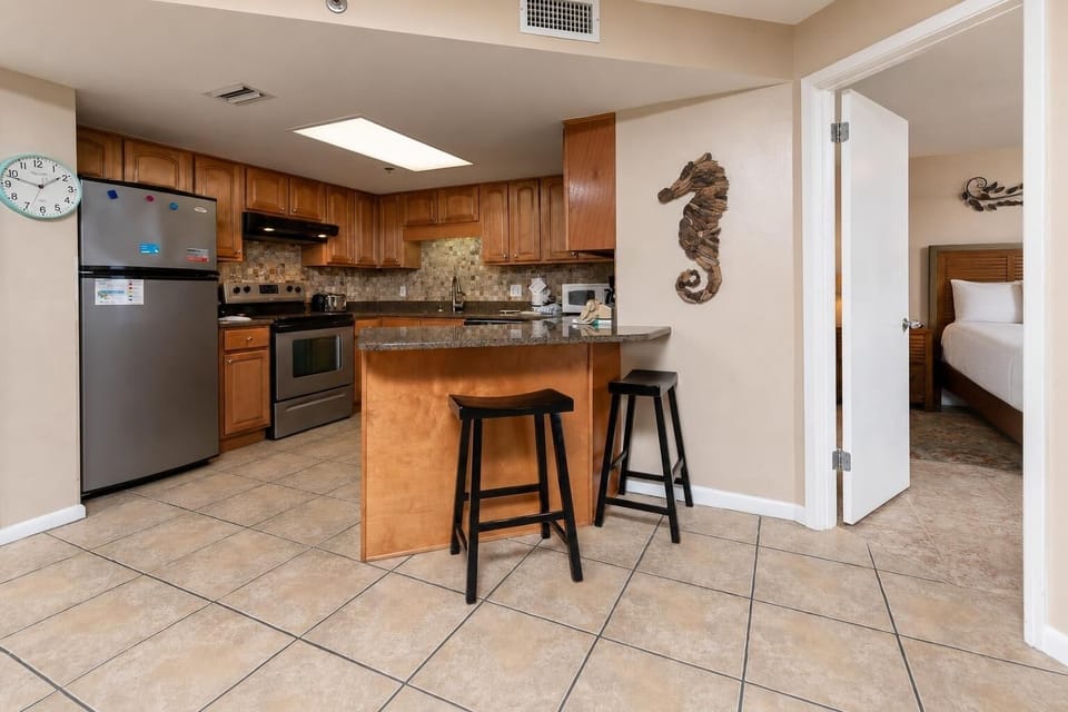 Warm wood cabinetry complements the granite counter in this inviting kitchen area, featuring a breakfast bar with seating