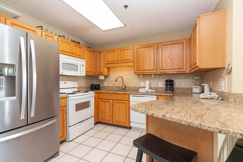 kitchen with wooden cabinetry, marbled countertops, and a breakfast bar featuring a black stool for casual dining
