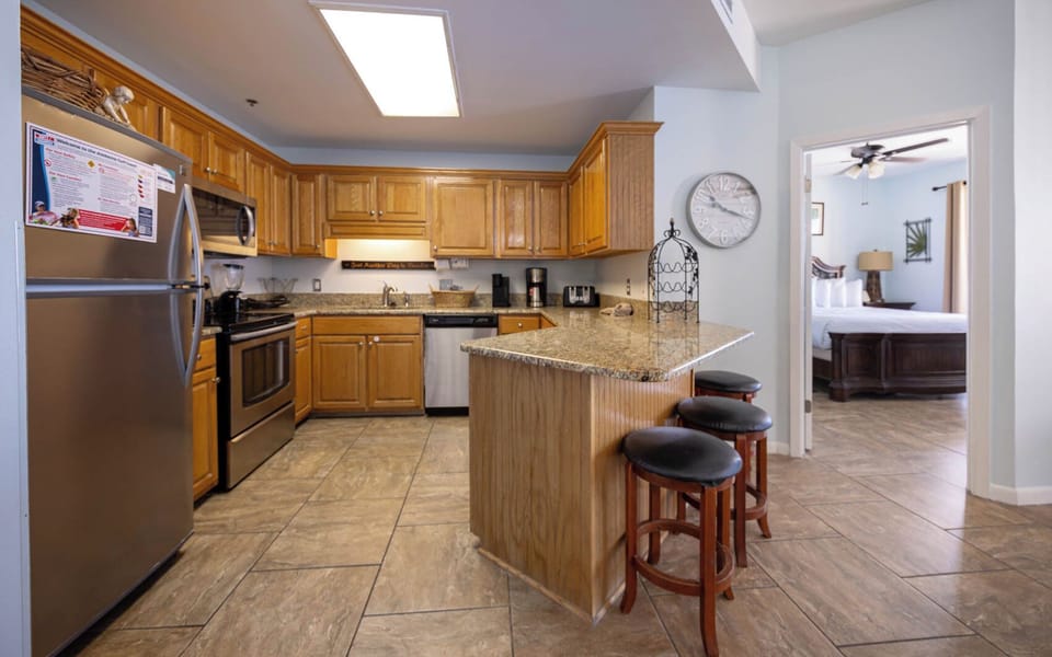 The modern kitchen features warm wooden cabinetry, a stylish countertop, and a breakfast bar with seating for casual dining