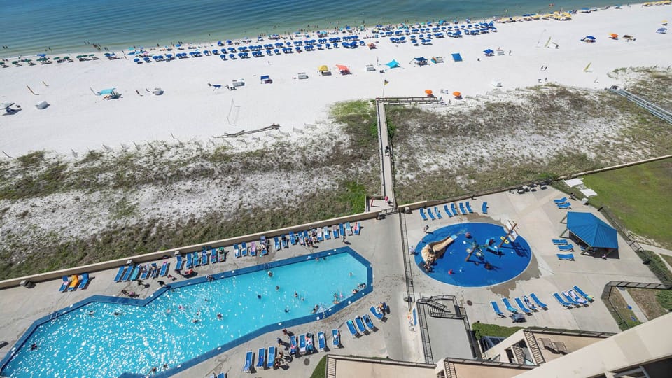 The vibrant pool area with a pirate ship splash park surrounded by lounge chairs, and a pristine beach just beyond