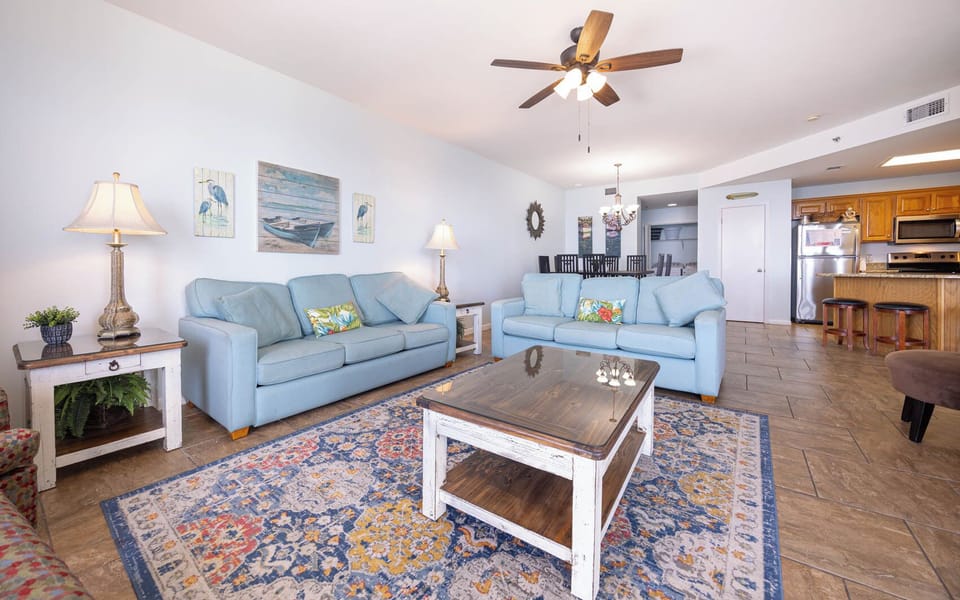 Bright living area features light blue sofas with a queen sleeper and decorative rug, creating a welcoming and relaxing vibe