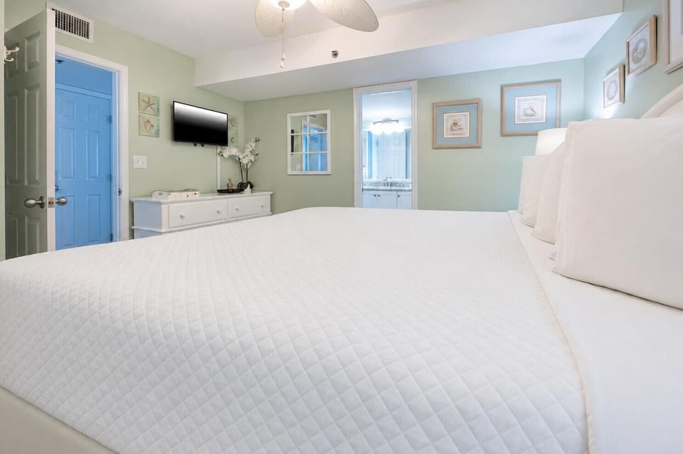 Relax in this serene bedroom featuring an inviting king bed, soft green walls, and a flat-screen TV for your entertainment