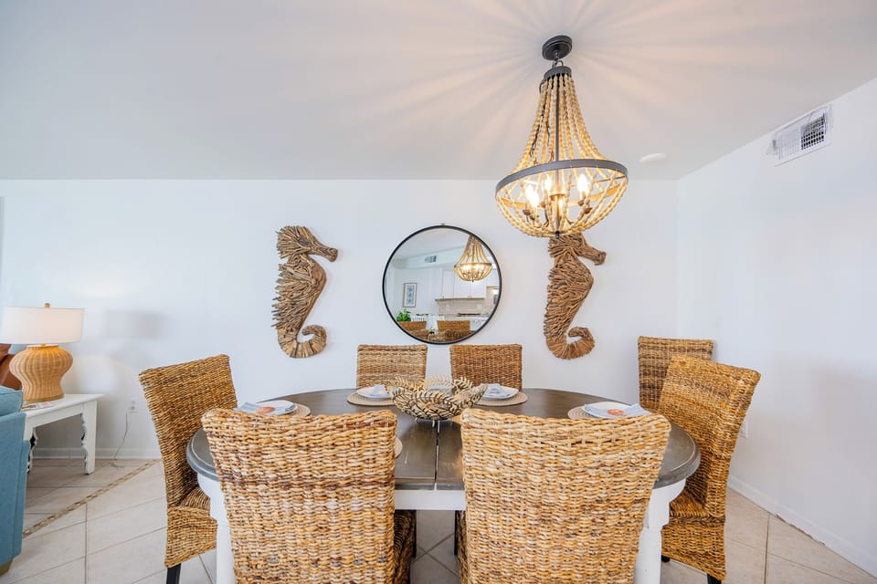 Gather around the dining table with rattan chairs and admire coastal art while sharing meals and stories