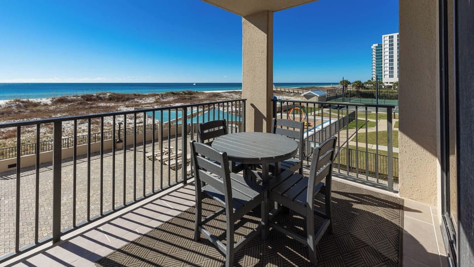 Savor meals at the outdoor table while enjoying views of the beach and nearby pool area from this inviting balcony