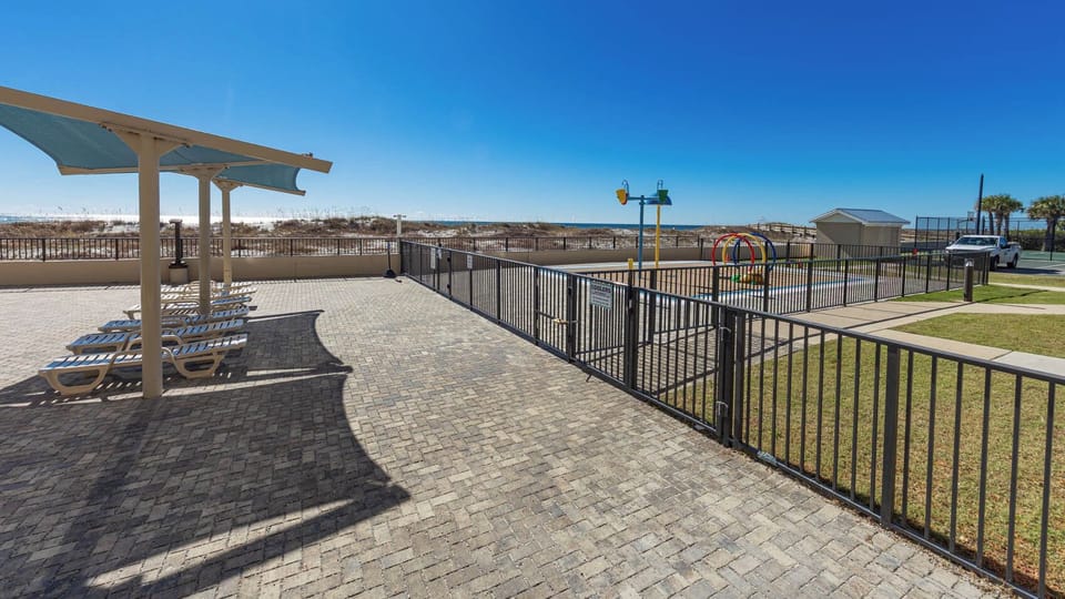 Lounge under shaded areas by the pool, enjoying views of the beach and nearby splash park for family fun