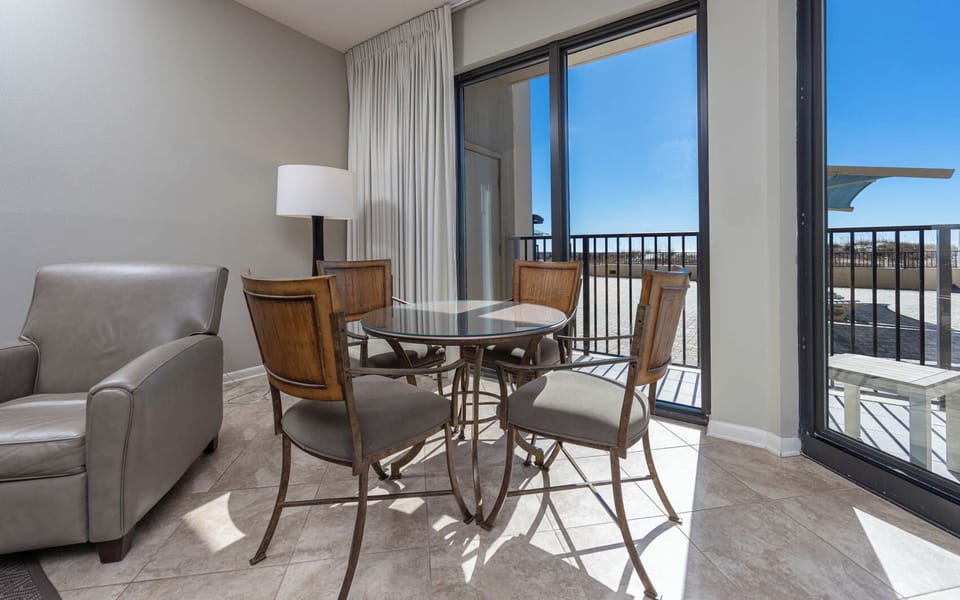 Dine at the glass-top table surrounded by stylish chairs, with natural light streaming in from the patio