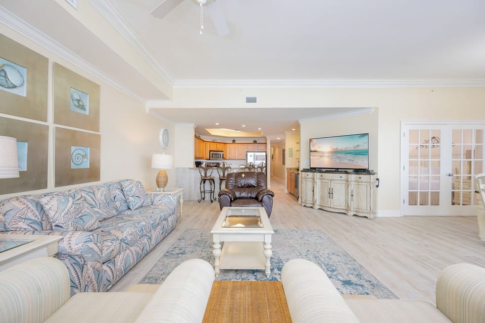 Bright and inviting living area featuring a cozy sofa with queen sleeper, large TV, and easy access to a modern kitchen