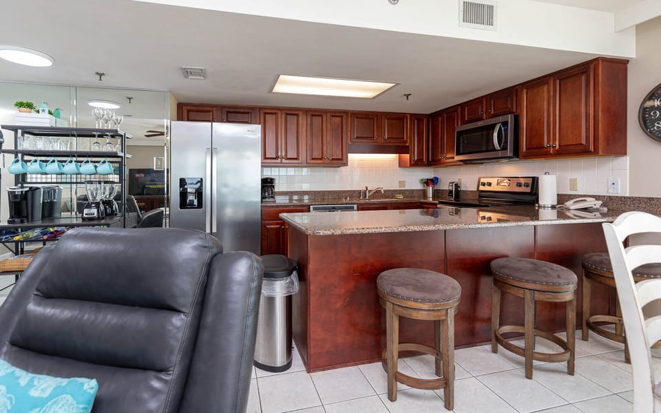 The kitchen features dark wood cabinetry, a granite countertop, and a breakfast bar with seating for casual dining