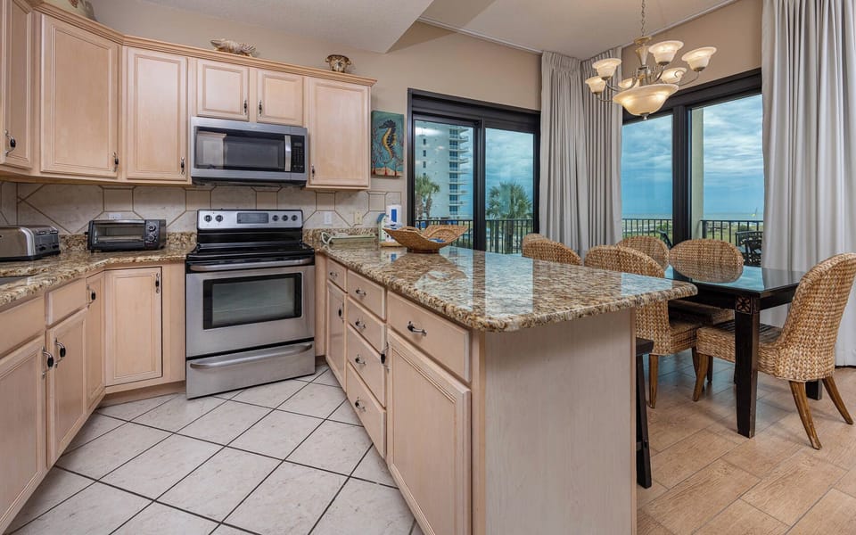 Modern kitchen with granite countertops, a breakfast bar, and stainless appliances offering views of the beach