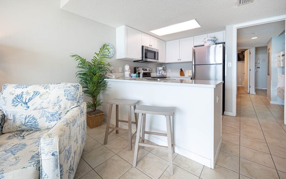 Enjoy a bright kitchen area with modern appliances, bar seating, and coastal-themed decor for a relaxing stay