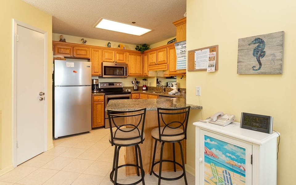 Brightly colored kitchen features wooden cabinetry, stainless appliances, and a breakfast bar for convenient entertaining