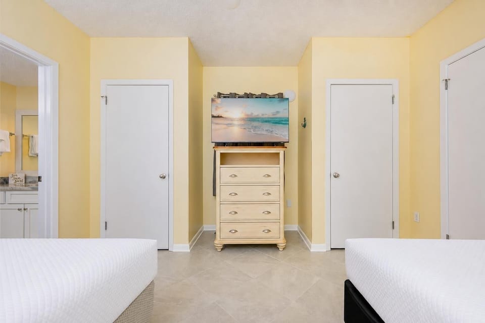 Guest suite with two double beds faces a dresser and TV for streaming your favorite shows