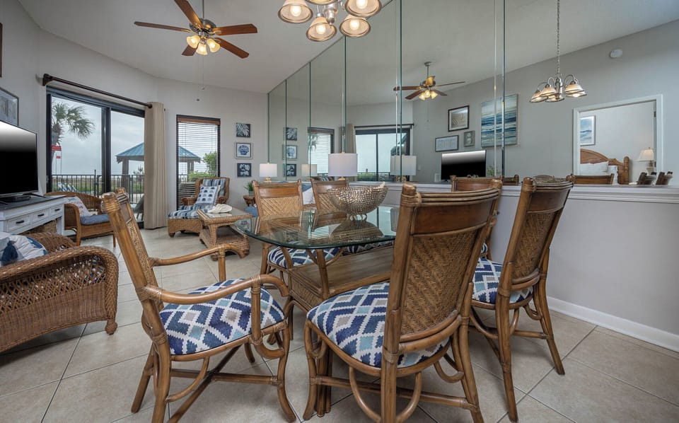 Enjoy meals at the glass dining table surrounded by comfortable rattan chairs, with a view of the beachfront patio