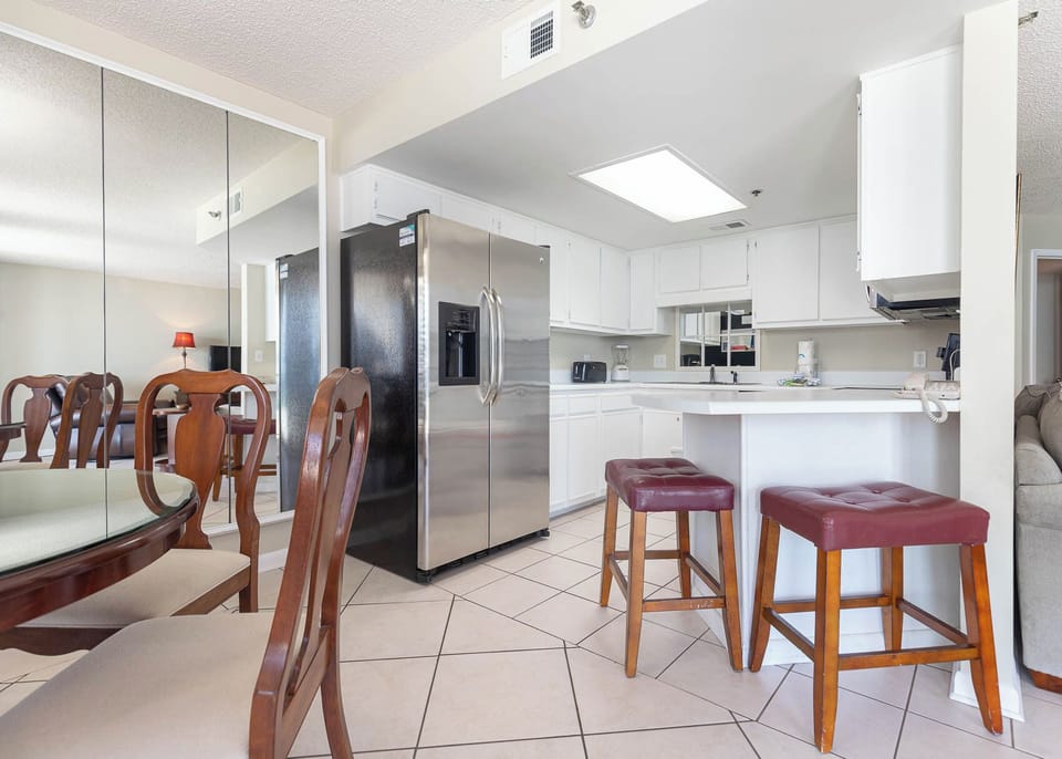 Gather around the glass dining table, enjoying meals with a view of the inviting kitchen
