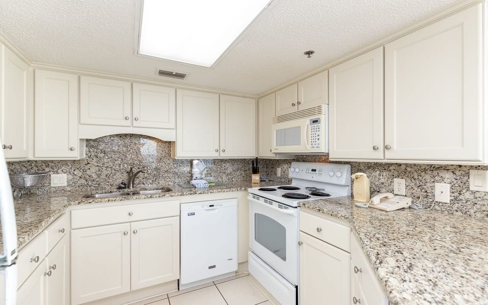 Bright kitchen featuring white cabinetry, stylish countertops, and essential appliances for a convenient cooking experience